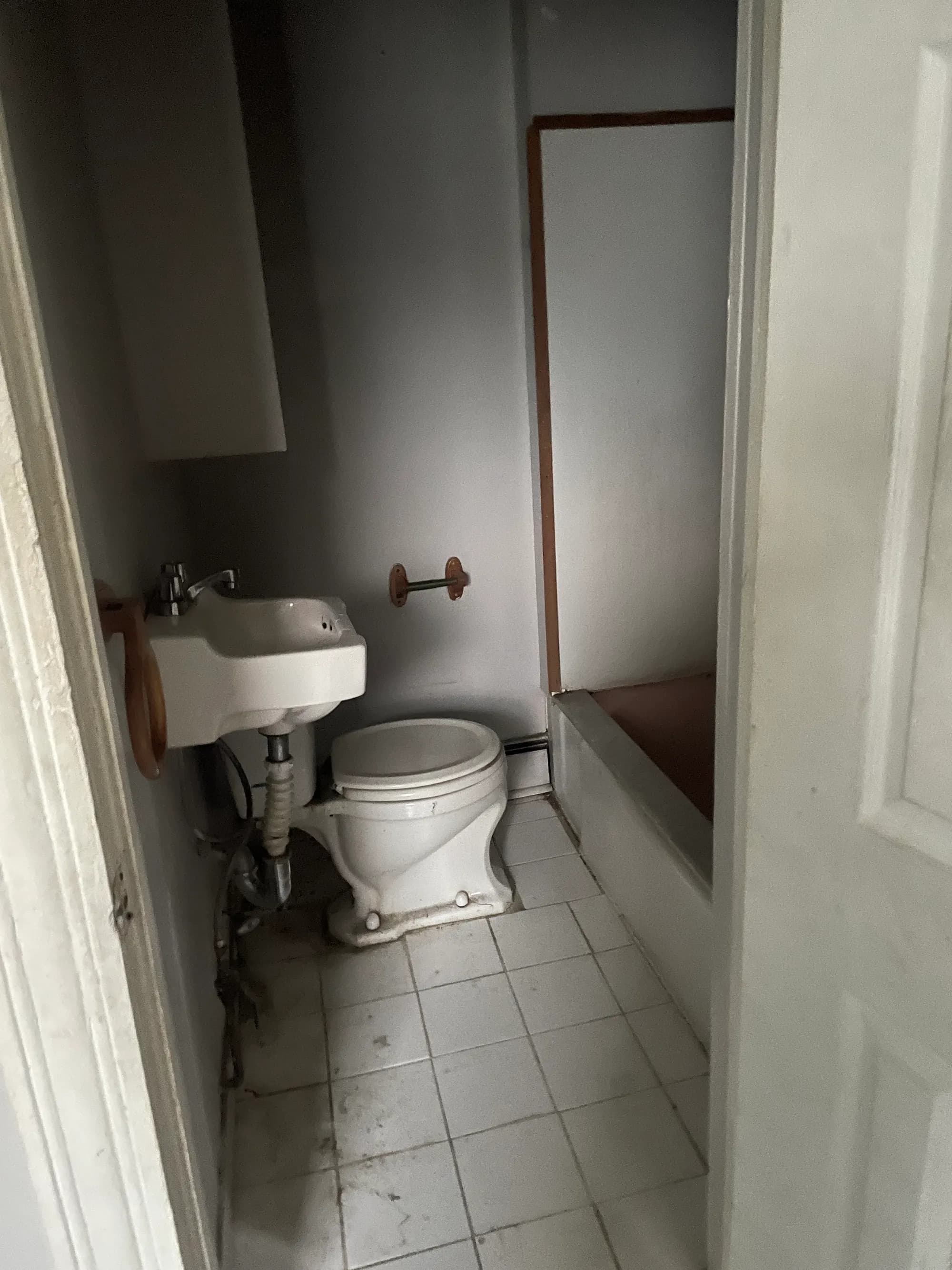 A bathroom being demolished, with the toilet and sink removed.