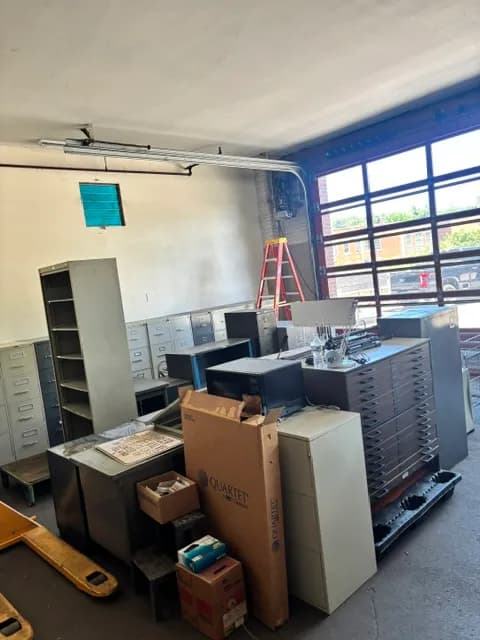 An office being cleared, with metal filing cabinets, boxes, and a step ladder.